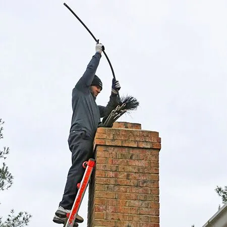 professional standing on ladder cleaning chimney