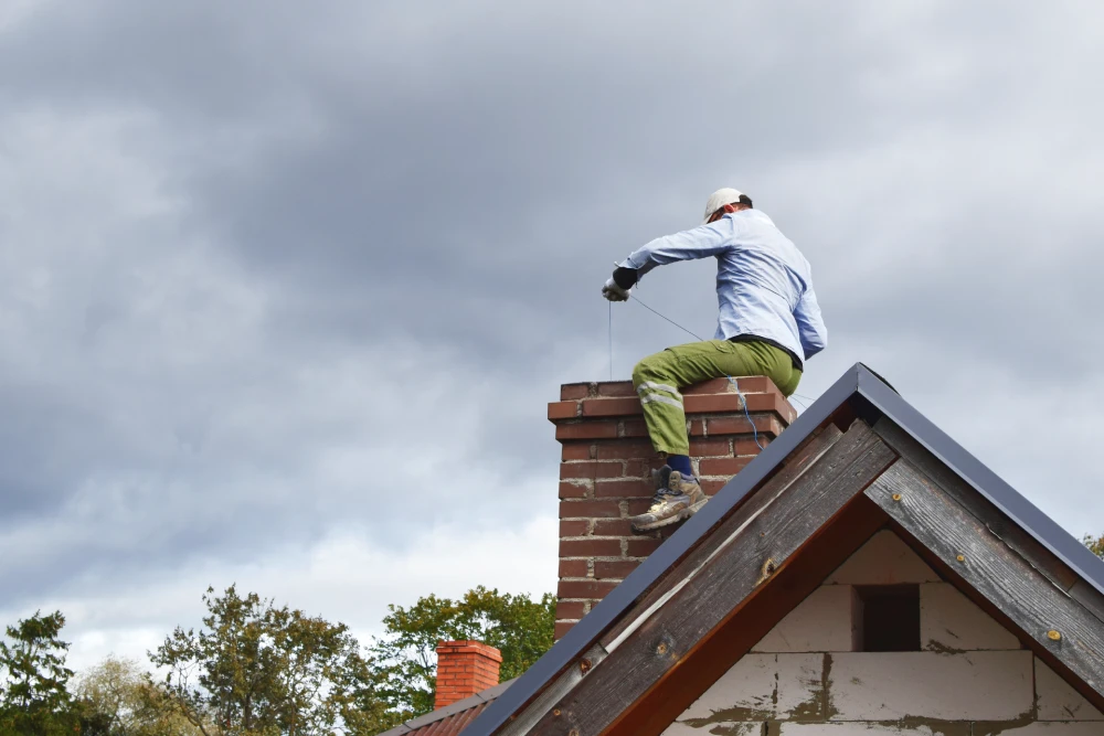 professional sitting on chimney and cleaning